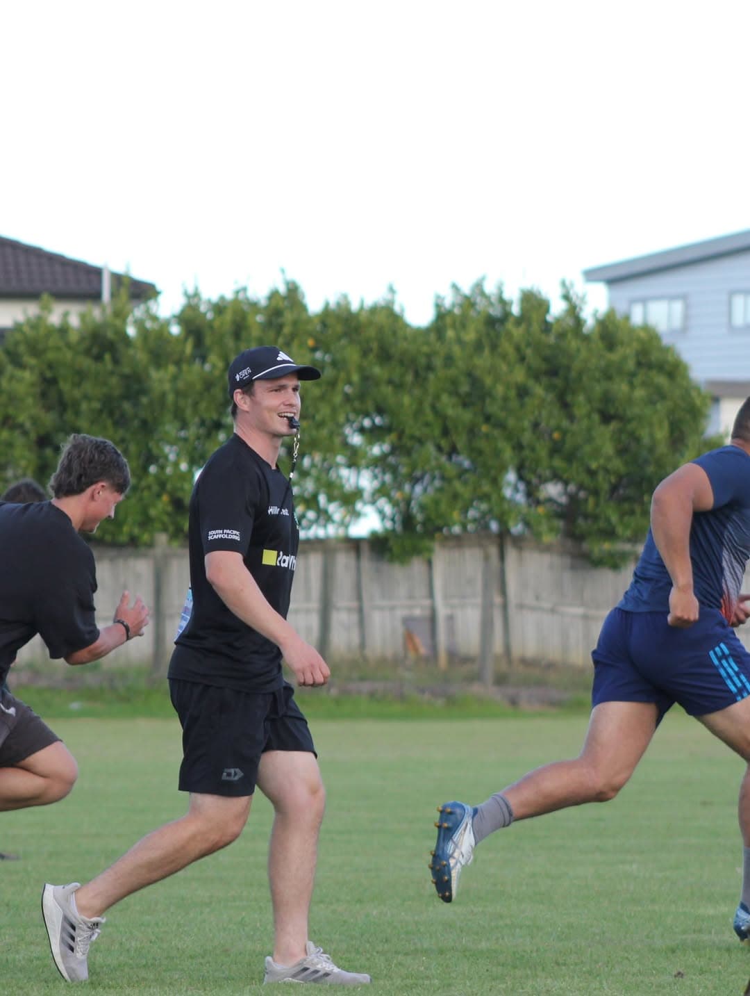 Coach running alongside athletes during a field session